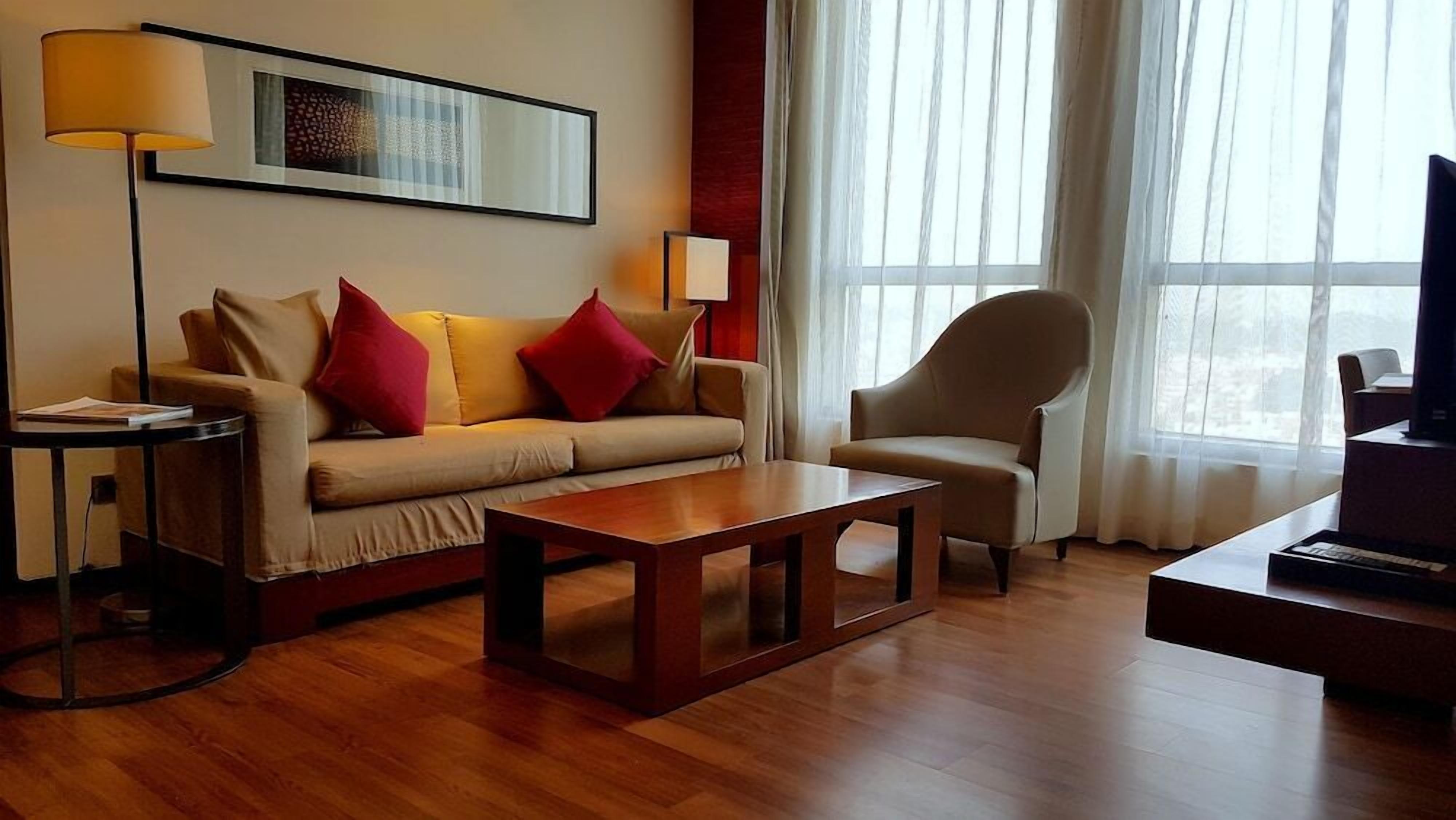 A living room with a sofa, armchair, coffee table, and a TV.