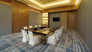 A conference room with a long table, white chairs, a flat-screen TV, and a patterned carpet. - Hyatt Regency Amritsar Hotel & Spa (Amritsar)