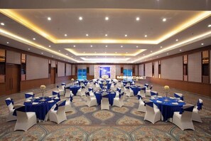 A large conference room with multiple round tables, each set with white chairs and blue tablecloths. The room features a patterned carpet and recessed lighting on the ceiling. - Hyatt Regency Amritsar Hotel & Spa (Amritsar)