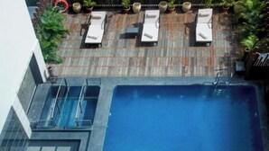 Un espace piscine aménagé sur le toit, avec des chaises longues et des plantes en pot.