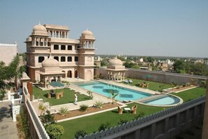 Un grand bâtiment doté d’une piscine, entouré d’une pelouse bien entretenue et agrémenté d’espaces aménagés pour s’asseoir.