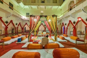 A hotel lobby with a central seating area, multiple balconies, and a decorative archway. - Mandawa Castle (Jhunjhunu)
