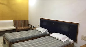 A room with two single beds, a sofa, and a chair. - Shanbhag Towers International (Hospet)