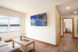 Quarto com uma mesa de madeira, um quadro pendurado na parede e vista para o exterior por uma grande janela.
