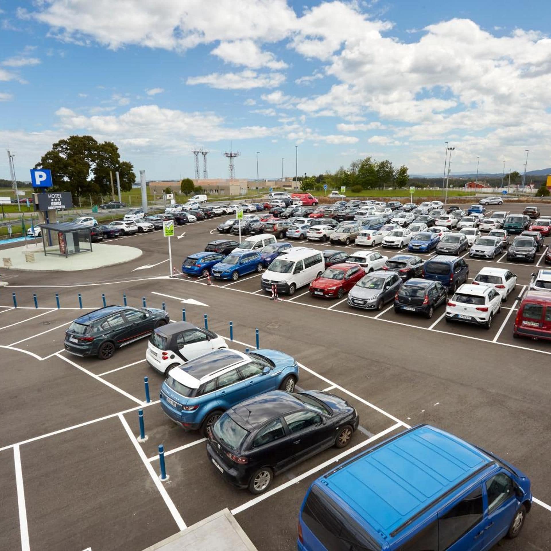 A parking lot with multiple cars and a hotel sign.