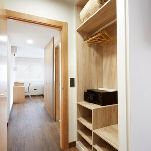 A hallway with a wooden wardrobe, a microwave on a shelf, and a desk with a chair. - Cristal Aeropuerto (Castrillon)