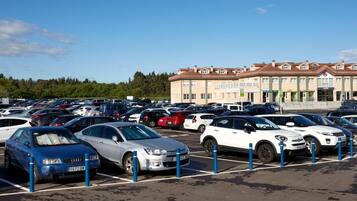A parking lot with multiple cars and a hotel building in the background.