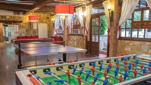 Egy szoba, amelyben van egy asztalfocsi asztal, egy pingpongasztal és egy kőből készült fal.