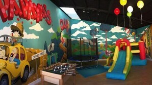 Un'area giochi per bambini con un tavolo da calcio, un trampolino e uno scivolo.