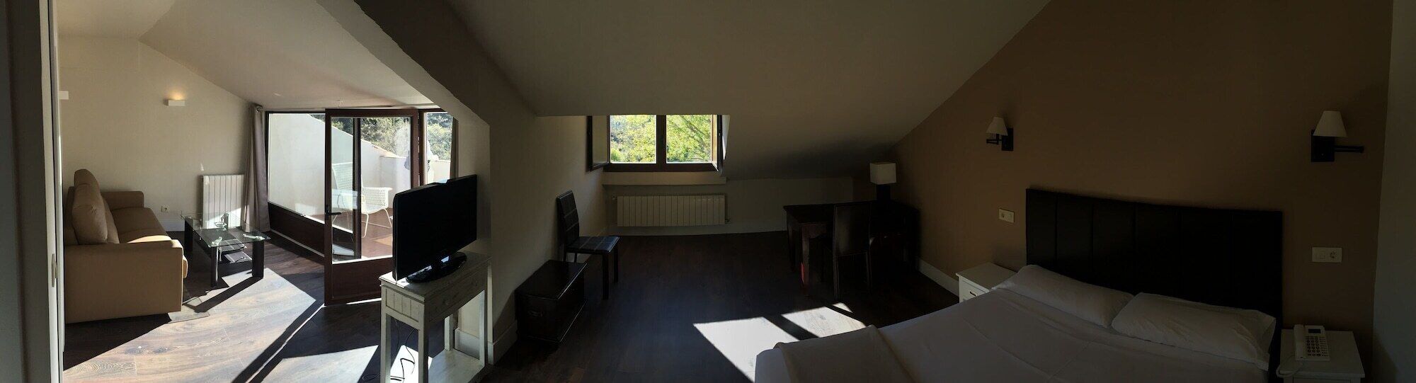 Un dormitorio con cama, mesita de noche, lámpara y ventana.