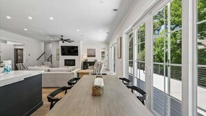 A modern interior with a dining area, kitchen, and large windows. - Spacious 7BR, New Build, Near Ocean, Private Pool, Elevator, Free Golf (Hilton Head Island)