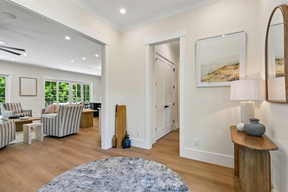 A spacious living room with a large window, a sofa set, and a wooden floor.