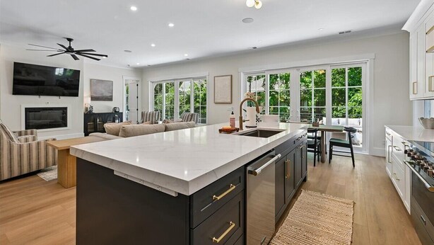 A spacious kitchen with a large island, a dining area with a table and chairs, and a living area with a sofa and TV. - Spacious 7BR, New Build, Near Ocean, Private Pool, Elevator, Free Golf (Hilton Head Island)