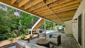 An outdoor patio with wooden beams, a pool, and seating areas. - Spacious 7BR, New Build, Near Ocean, Private Pool, Elevator, Free Golf (Hilton Head Island)
