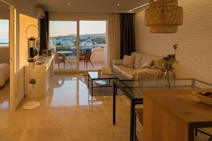 Una sala moderna con sofá, mesa de centro y una mesa de comedor con cubierta de vidrio. Hay un balcón con vistas a un paisaje nevado.
