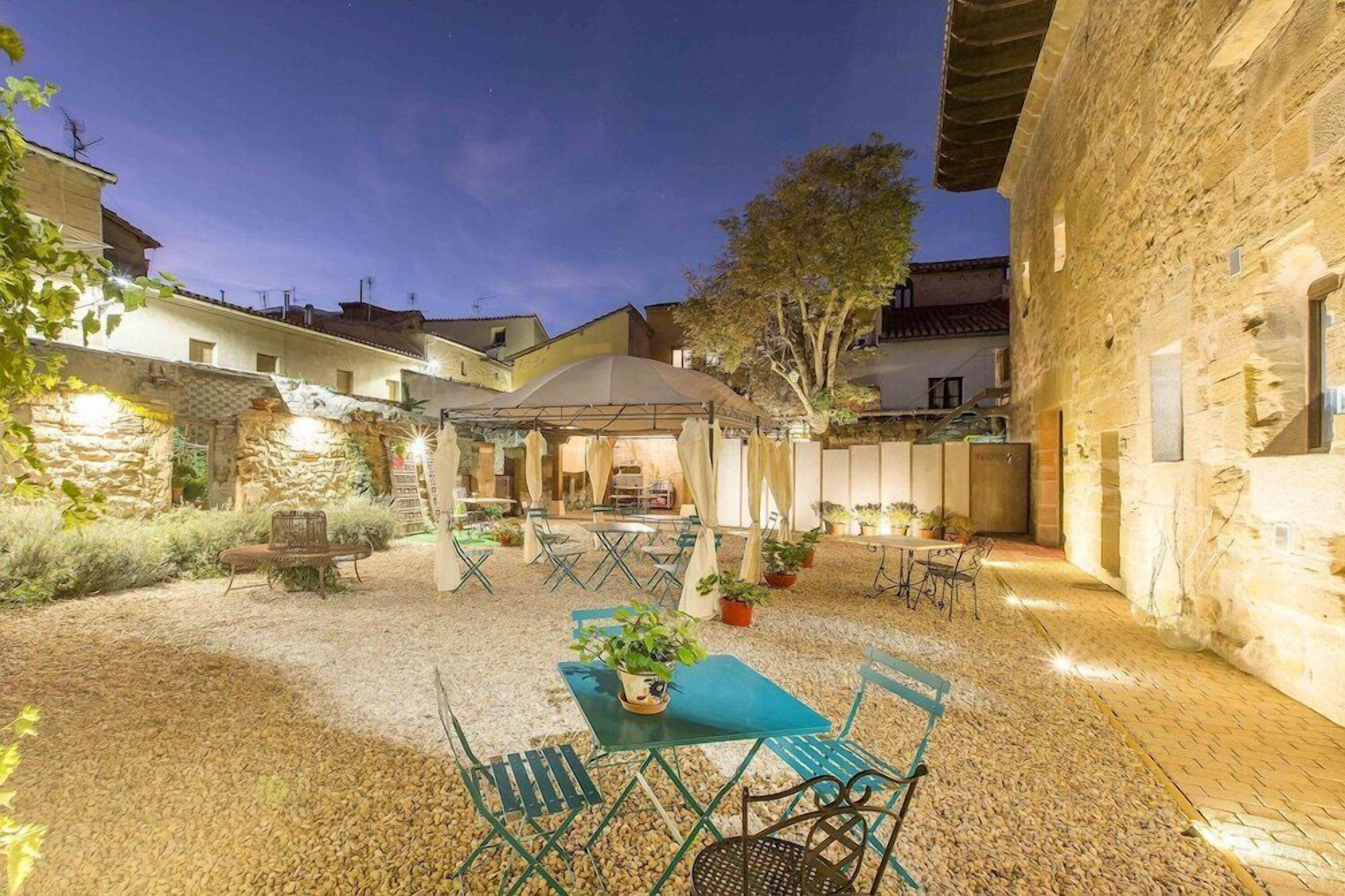 A courtyard with outdoor seating, stone buildings, and a covered area.