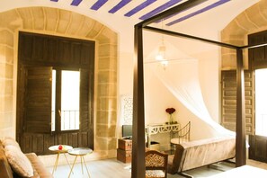 A bedroom with a bed, a desk, and a chair. There is a window with curtains and a mirror on the wall. - Hotel Teatrisso (Cuzcurrita de Rio Tiron)
