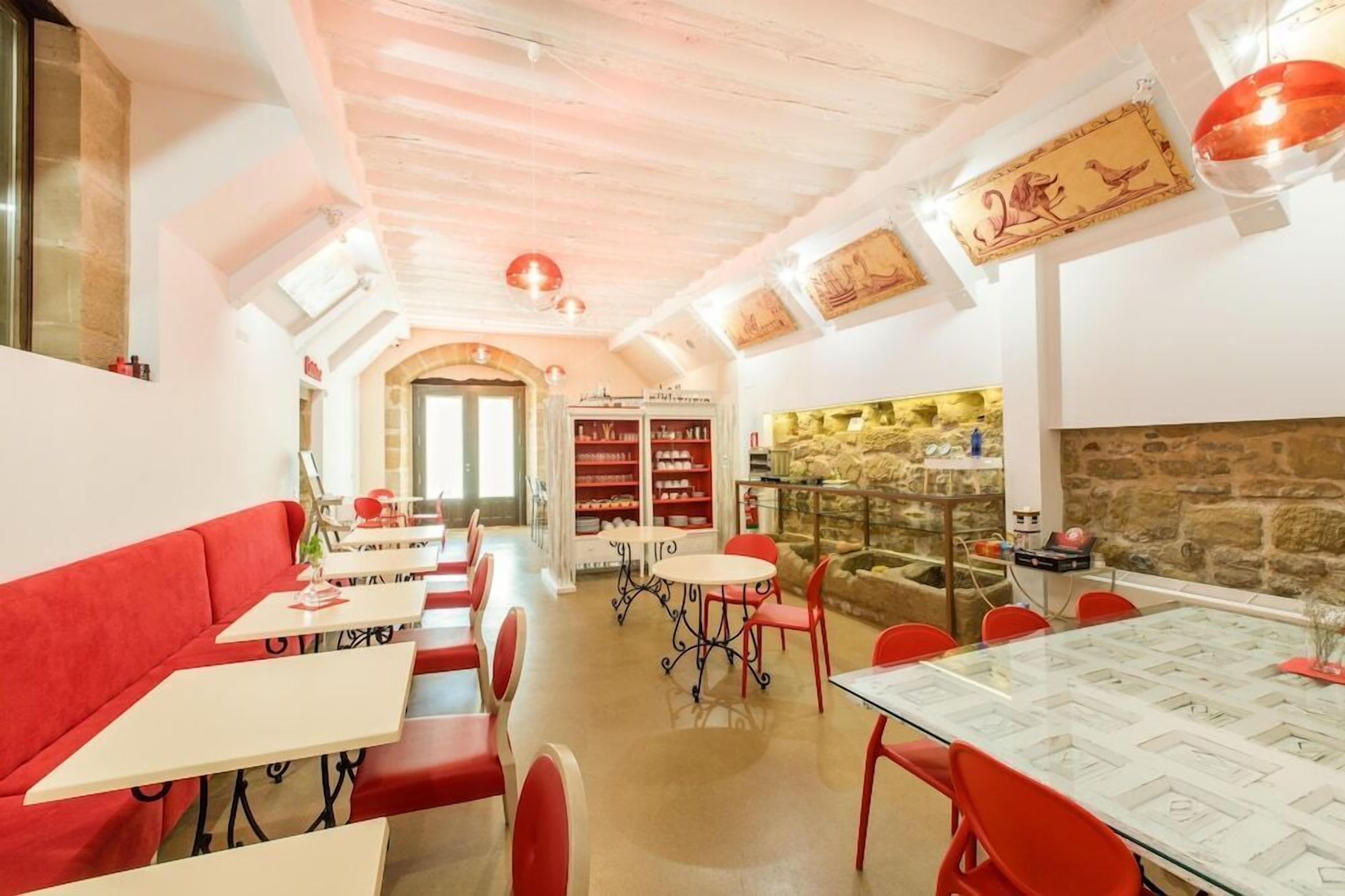 Un restaurant amb seients vermells, una paret de pedra i una prestatgeria.