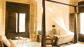 A bedroom with a bed, a desk, and a chair. There is a window with curtains and a mirror on the wall. - Hotel Teatrisso (Cuzcurrita de Rio Tiron)