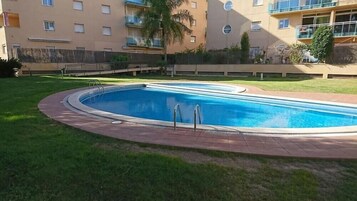 Una piscina rectangular con borde curvo, rodeada por un camino empedrado.