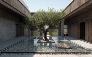 A courtyard with a tree, pebbles, and a water feature. - Aldiana Club Costa del Sol (La Línea de la Concepción)