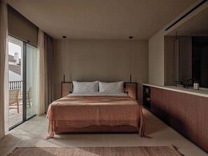 Un dormitorio con una cama grande, una puerta corrediza al balcón, una mesita de noche de madera y un espejo.