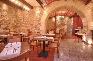 A restaurant with stone walls, wooden tables, and chairs.