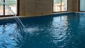 An indoor swimming pool with clear views of buildings and hills through large windows. - Don Juan de Austria (Jarandilla de la Vera)