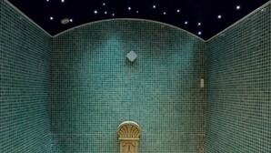 A room with a tiled floor and walls, a bench, and a decorative element on the wall. - Don Juan de Austria (Jarandilla de la Vera)