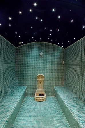 A room with a tiled floor and walls, a bench, and a decorative element on the wall. - DON Juan DE Austria (Jarandilla de la Vera)