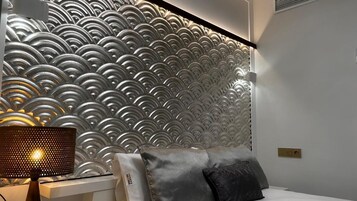 Un dormitorio moderno con un panel de pared texturizado, una lámpara de noche y una cama con almohadas.