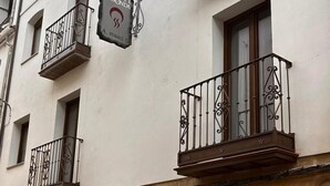 Un edificio con varios balcones, un letrero que dice 'FUEGNE REDONDA' y un cartel azul que indica un hospital cercano.