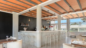A modern bar area with a counter, bar stools, and a wine display. - Apartamentos Vibra Caleta Playa (Ciutadella de Menorca)