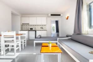 A compact living space with a dining area, a sofa, and a small kitchen. - Apartamentos Vibra Caleta Playa (Ciutadella de Menorca)