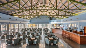 A spacious indoor area with a high ceiling and a bar area on the right. - Apartamentos Vibra Caleta Playa (Ciutadella de Menorca)