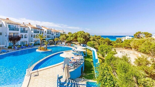 A resort with a large swimming pool, multiple balconies, and a view of the sea. - Apartamentos Vibra Caleta Playa (Ciutadella de Menorca)