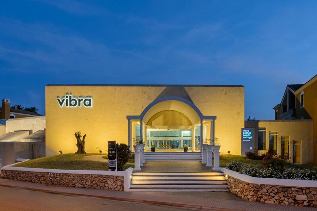 Een gebouw met een 'vibra' bord, een pad van stenen en een goed verlichte ingang.