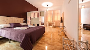 A modern bedroom with a large bed, a desk, and a chair. There is a mirror on the wall and a hanging light fixture. - Hotel Las Palmas Urban Center (Las Palmas de Gran Canaria)