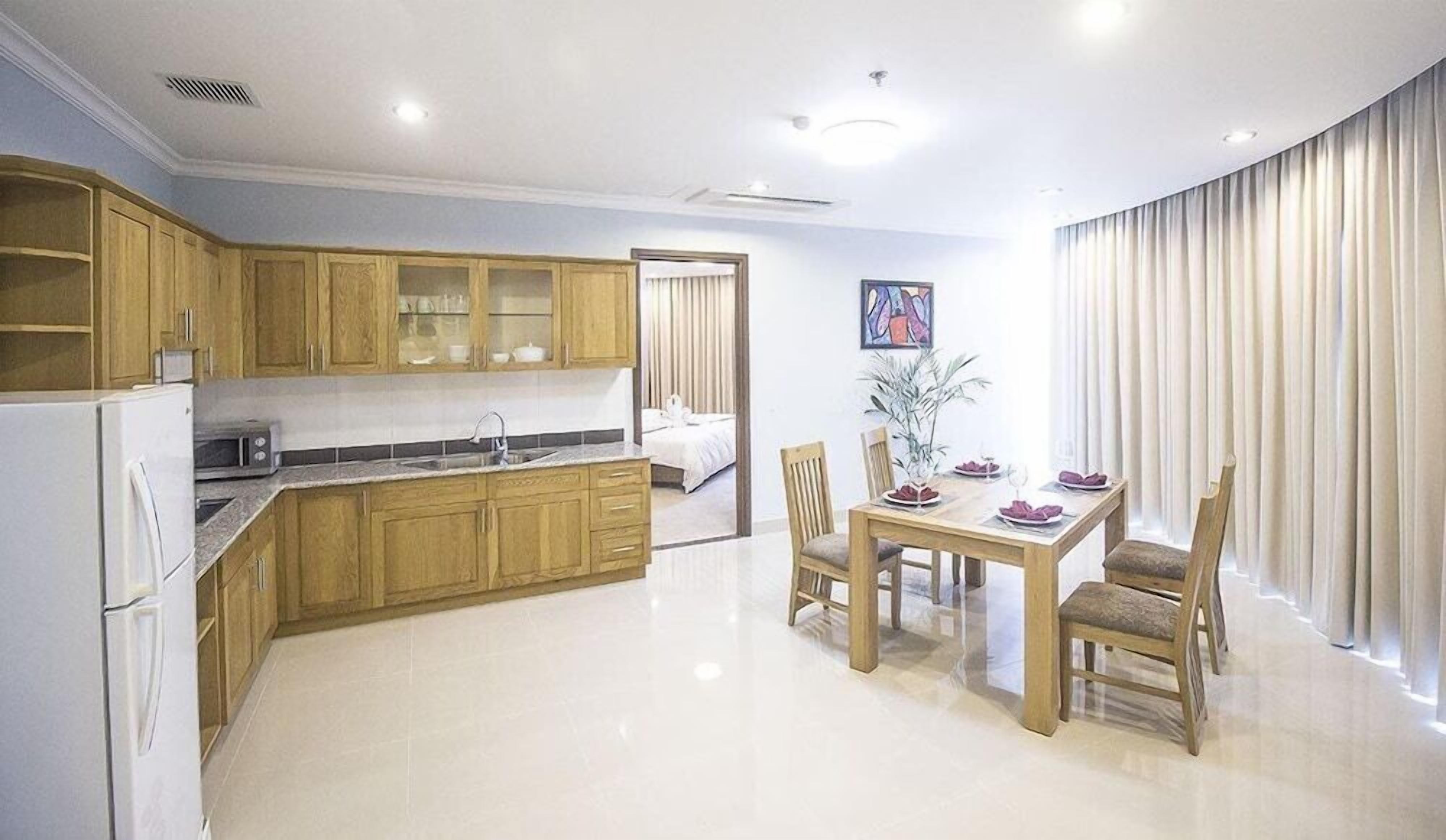 A modern kitchen with wooden cabinets, a dining table with chairs, and a large window with curtains.