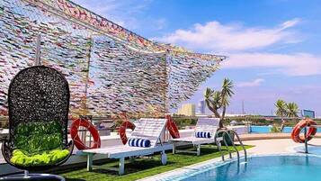 A poolside area with lounge chairs, a decorative wall, and a clear sky.