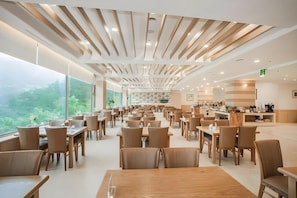 A spacious dining area with multiple tables and chairs, large windows with a view of greenery, and a modern ceiling design. - Il Sung Jirisan Resort (Namwon)