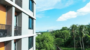 A multi-story building with balconies, surrounded by lush greenery and palm trees. - B2 Phuket (Ratsada)