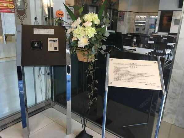 Un'area receptione con una parete divisoria in vetro, un'esposizione floreale e un cartello.
