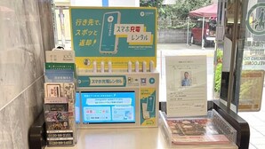 Quiosco de alquiler de baterías portátiles con pantalla digital que muestra información y un letrero con texto en japonés.