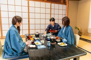 A traditional Japanese room with tatami flooring, a low table with various dishes, and a shoji screen in the background. - Yamaki Ryokan (Atami)