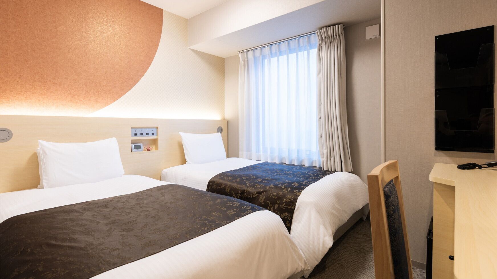 Une chambre d’hôtel avec deux lits, une télévision, un bureau et une fenêtre avec des rideaux.