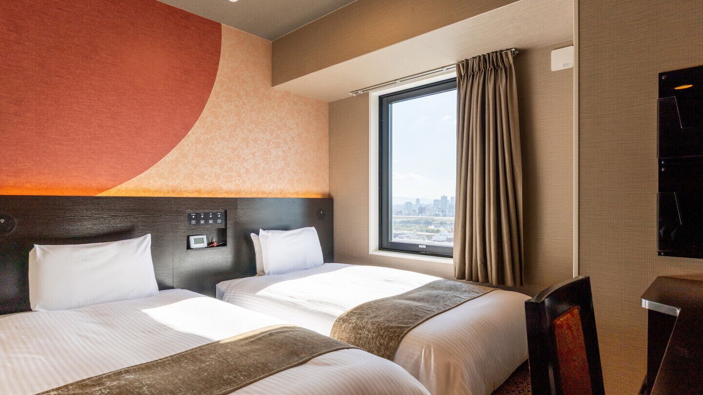 Une chambre d’hôtel avec deux lits, une grande fenêtre avec des rideaux, un téléviseur à écran plat et une vue sur la ville.