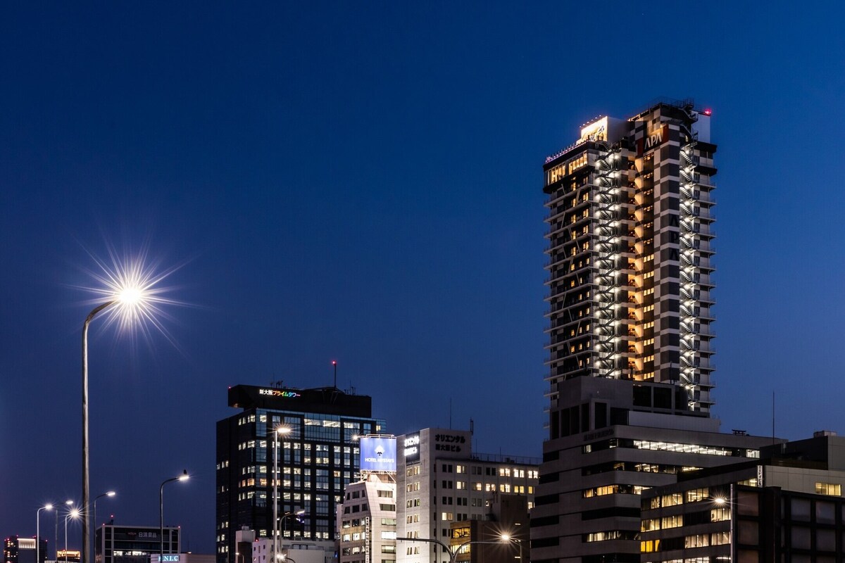 Een hoog hotel met meerdere verdiepingen, verlichte ramen en een opvallend 'APA'-bord op het gebouw.