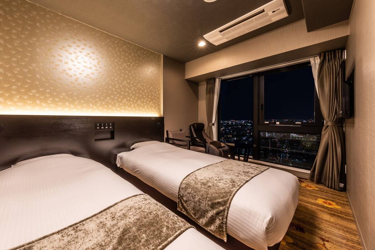 Une chambre d’hôtel avec deux lits, une vue sur la ville, un design moderne et un panneau de commande.