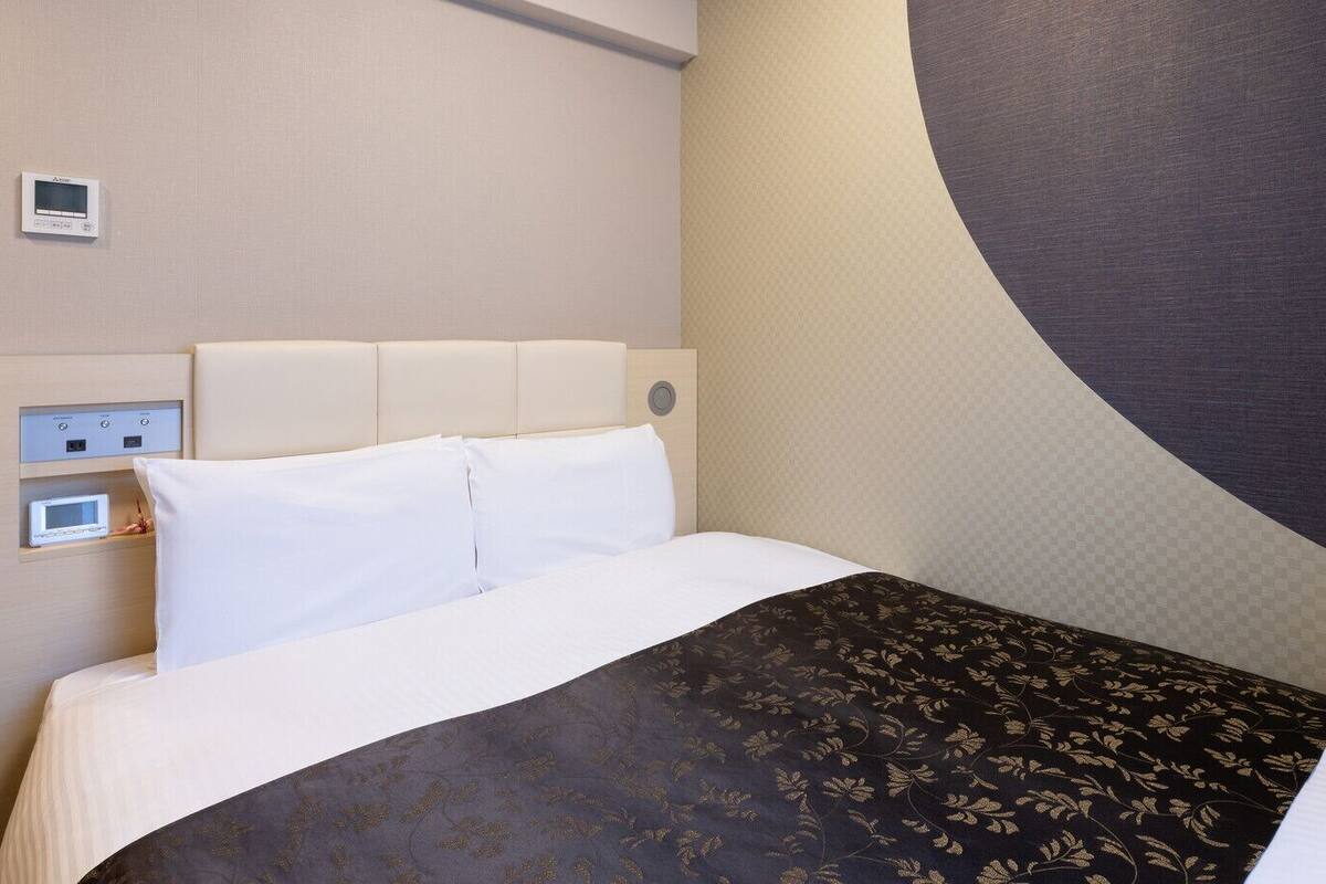 Une chambre d’hôtel avec un lit, un panneau de commande et une grande horloge murale.